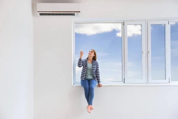 Jonge vrouw airconditioner thuis inschakelen — Stockfoto