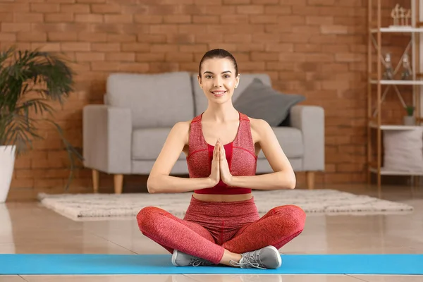 Sporty young woman practicing yoga at home — Stock Photo, Image