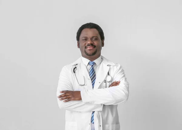 Male African-American doctor on light background — Stock Photo, Image