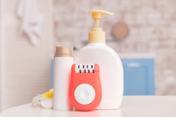 Modern epilator with cosmetics on table in bathroom — Stock Photo, Image