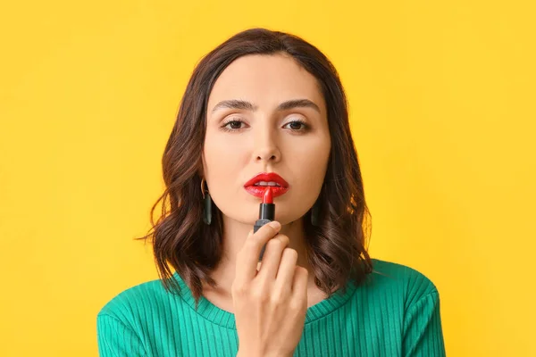 Hermosa joven aplicación de maquillaje en el fondo de color — Foto de Stock