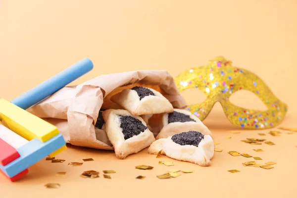 Tasty hamantaschen, gragger and party decor for Purim holiday on color background — Stock Photo, Image
