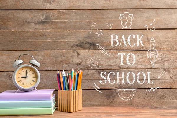 Set de papelería, reloj y texto REGRESAR A ESCUELA sobre fondo de madera — Foto de Stock