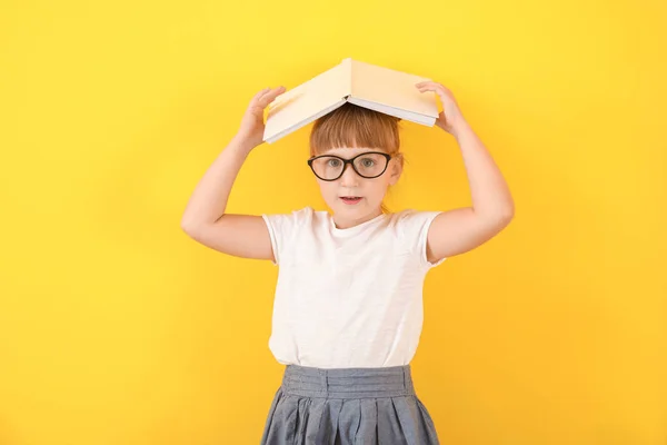 Nettes kleines Mädchen mit Buch auf farbigem Hintergrund — Stockfoto