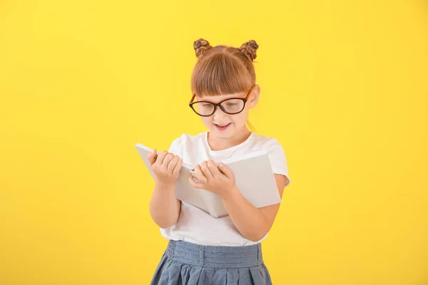 Carino bambina con libro su sfondo di colore — Foto Stock