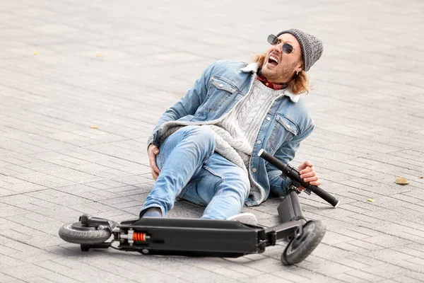 Unge man ramlade av sin sparkcykel utomhus — Stockfoto