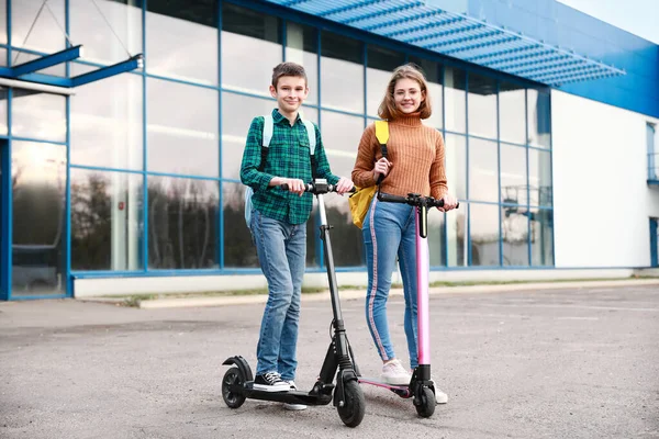 Active teenagers riding kick scooters outdoors — 스톡 사진