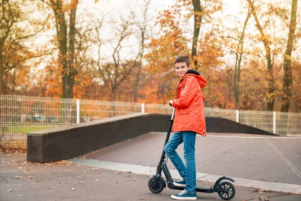 Remaja laki-laki naik skuter menendang di taman skate — Stok Foto