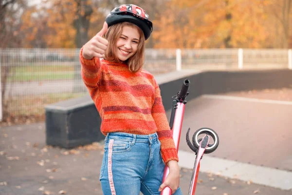 Teenage girl with kick scooter showing thumb-up in skate park — Stock Photo, Image