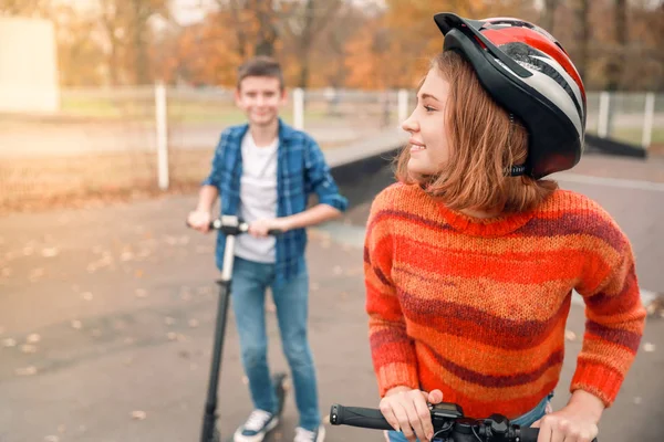 Active teenagers riding kick scooters in skate park — Stock Photo, Image