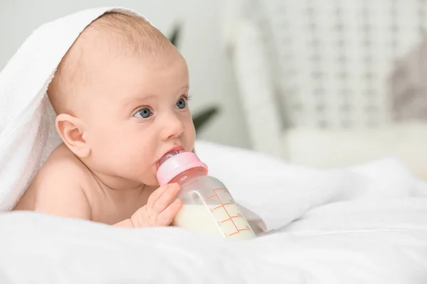 Портрет милої маленької дитини, що п'є молоко з пляшки на ліжку — стокове фото