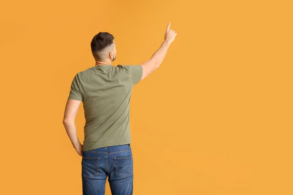 Hombre apuntando a algo en el fondo de color, vista posterior —  Fotos de Stock