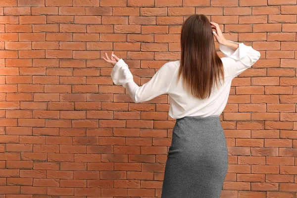 Thoughtful businesswoman against brick wall — Stock Photo, Image