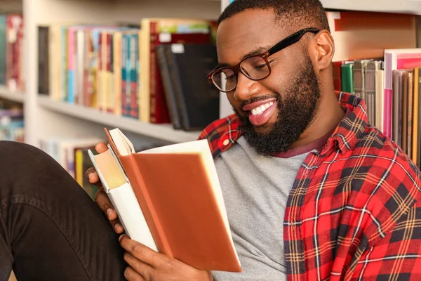Афроамериканский студент читает книгу во время подготовки к экзамену в библиотеке — стоковое фото