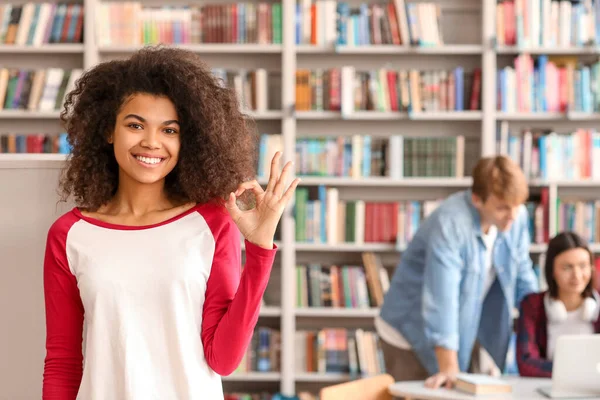 African-American student showing OK gesture in library