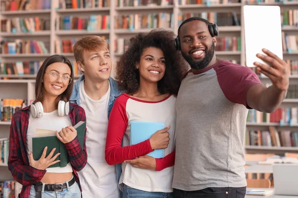 Jovens estudantes tirando selfie na biblioteca — Fotografia de Stock