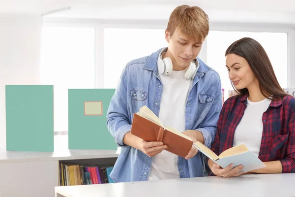 Young students reading books while preparing for exam in library — Stock Photo, Image