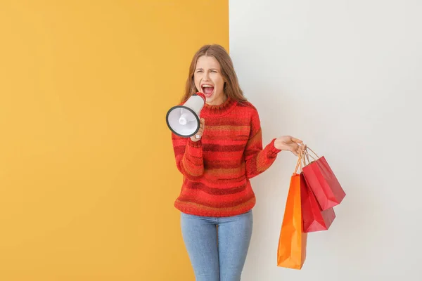Fiatal nő megafon és bevásárló táskák színes háttér — Stock Fotó