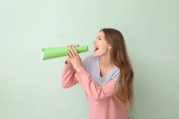Mujer joven con megáfono de papel sobre fondo de color —  Fotos de Stock