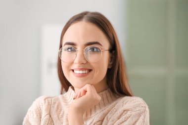 Evde şık gözlükleri olan genç bir kadın var.