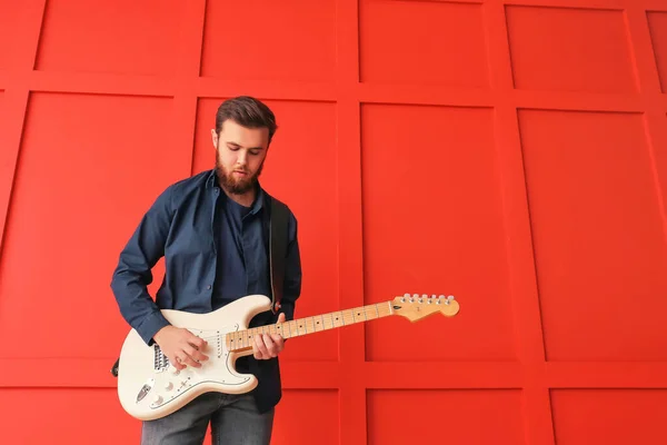 Giovane uomo che suona la chitarra vicino alla parete di colore — Foto Stock