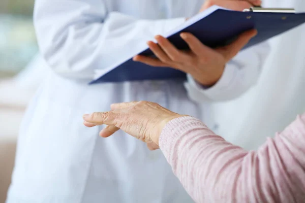 Female doctor working with senior woman suffering from Parkinson syndrome in clinic — 스톡 사진