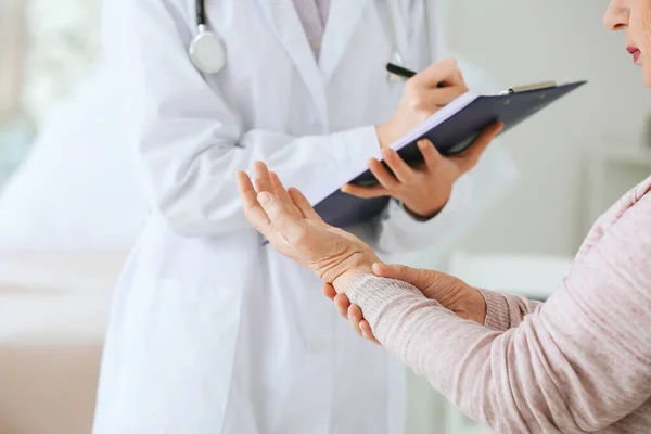 Lekarz pracujący z kobietą w podeszłym wieku cierpiącą na zespół Parkinsona w klinice — Zdjęcie stockowe