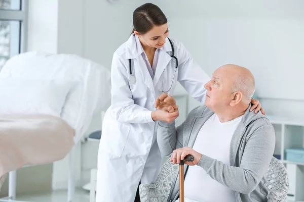 Médica com homem idoso que sofre de síndrome de Parkinson na clínica — Fotografia de Stock