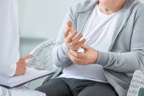 Medico donna che lavora con uomo anziano affetto da sindrome di Parkinson in clinica — Foto Stock