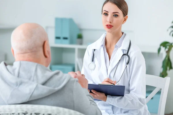 Female doctor working with senior man suffering from Parkinson syndrome in clinic — Stock Photo, Image