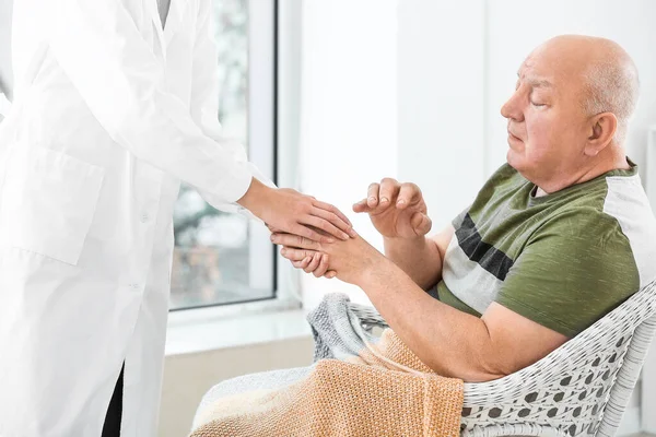 Medico femminile con uomo anziano affetto da sindrome di Parkinson in clinica — Foto Stock