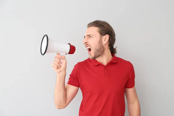 Screaming young man with megaphone on grey background — Stock Photo, Image