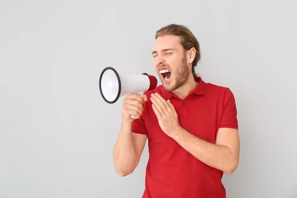 Screaming young man with megaphone on grey background — Stock Photo, Image