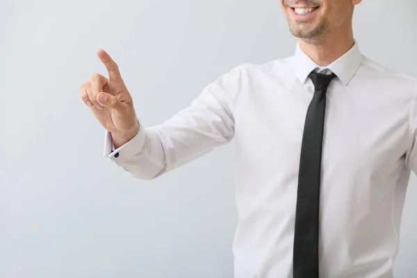 Joven hombre de negocios usando pantalla virtual sobre fondo gris — Foto de Stock