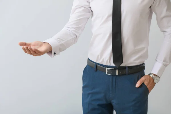 Joven empresario sosteniendo algo sobre fondo gris — Foto de Stock