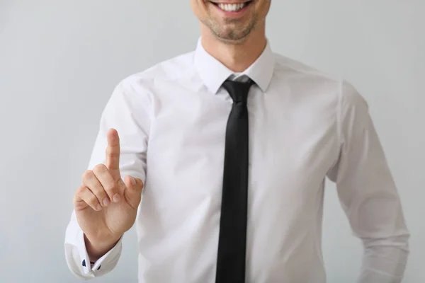 Young businessman using virtual screen on grey background — Stock Photo, Image