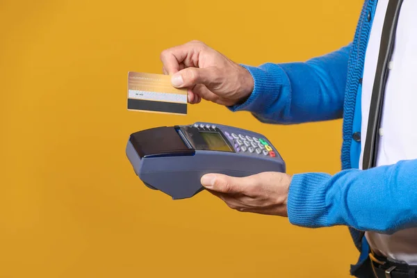 Чоловічий менеджер банку з кредитною карткою та платіжним терміналом на кольоровому фоні — стокове фото