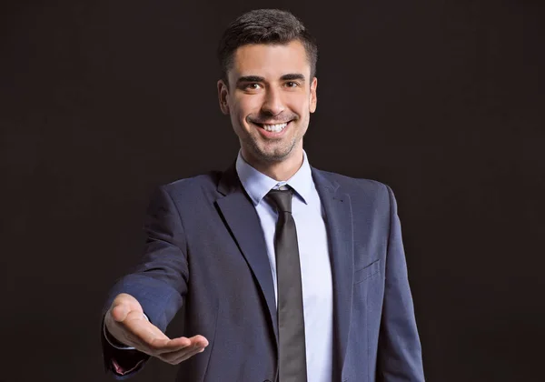 Joven hombre de negocios sosteniendo algo sobre fondo oscuro — Foto de Stock