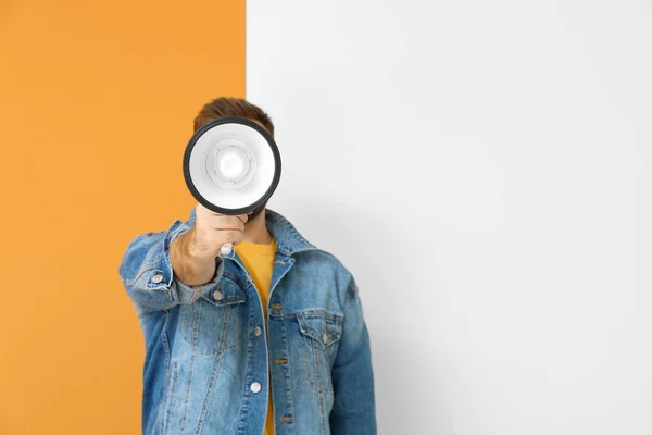Young man with megaphone on color background — Stock Photo, Image
