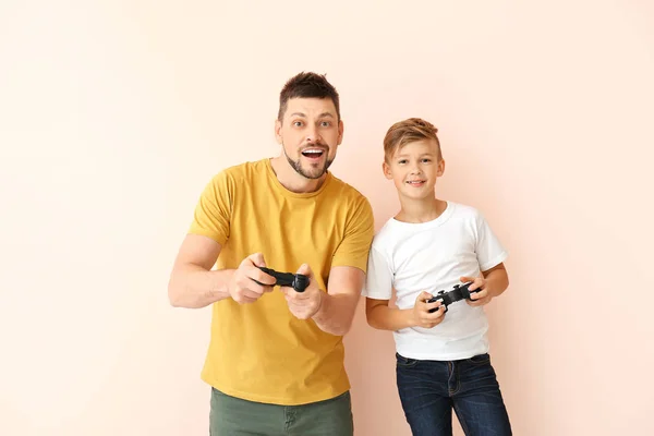 Ojciec i jego synek grają w gry wideo na kolorowym tle — Zdjęcie stockowe