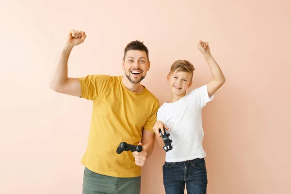 Apa és a kisfia videojátékokat játszik a színes háttér — Stock Fotó