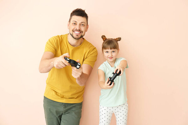 Отец и его маленькая дочь играют в видеоигры на цветном фоне

