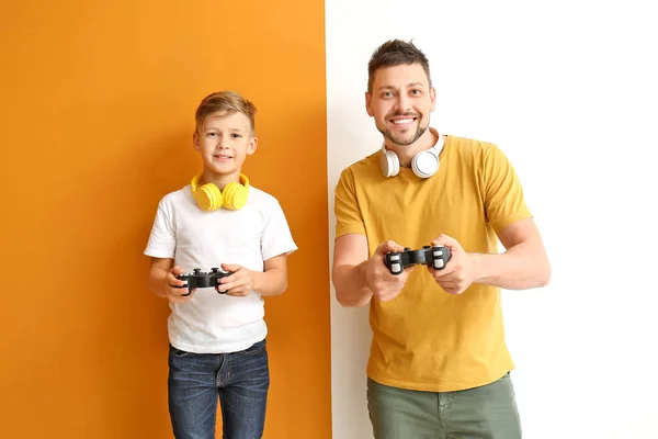 Father and his little son playing video games on color background — Stock Photo, Image