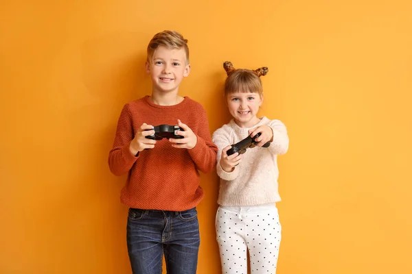 Little children playing video games on color background — Stock Photo, Image