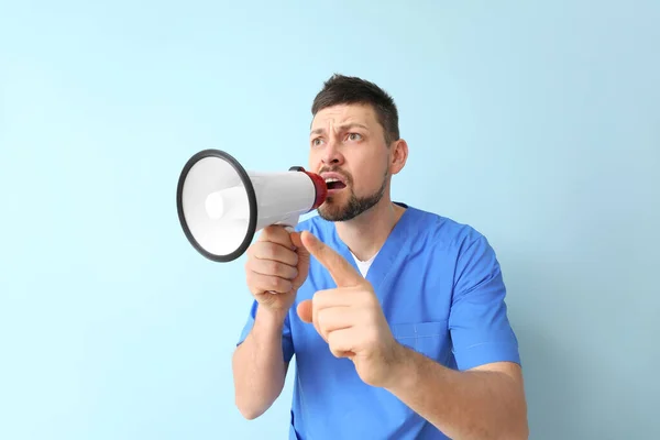 Emotional man with megaphone on color background — Stock Photo, Image