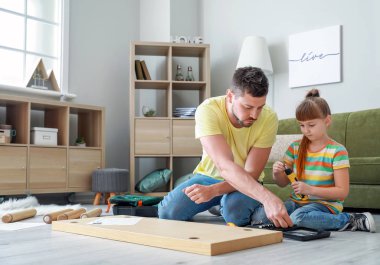 Babası ve küçük kızı evde mobilya montajı yapıyor.