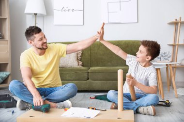 Babası ve küçük oğlu evde mobilya montajı yapıyor.