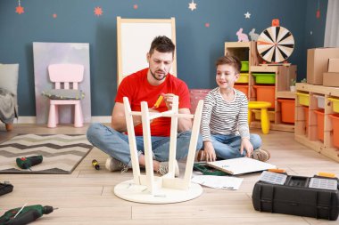 Babası ve küçük oğlu evde mobilya montajı yapıyor.