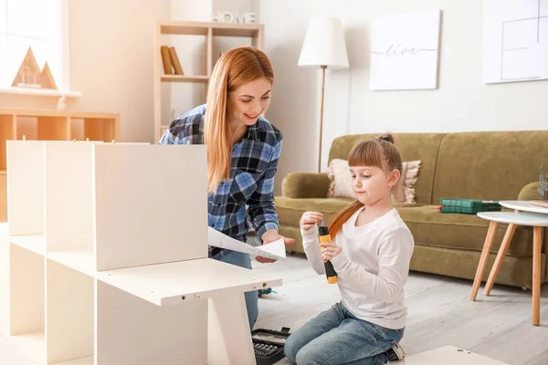Mother and her little daughter assembling furniture at home — Stock Photo, Image