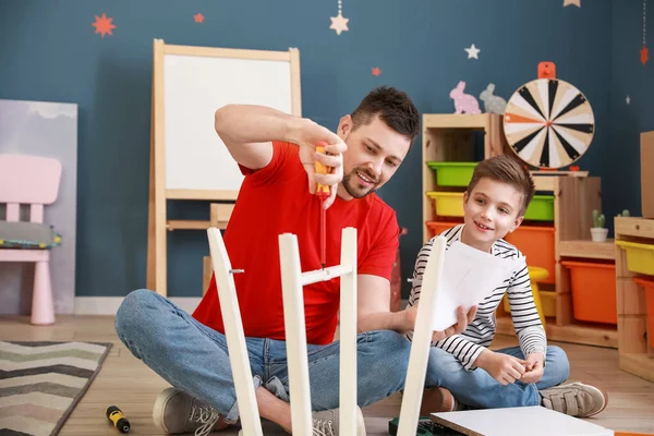 Father and his little son assembling furniture at home — Stock Photo, Image